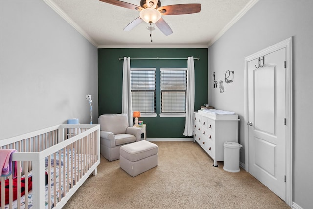 carpeted bedroom with crown molding, a nursery area, a textured ceiling, and ceiling fan