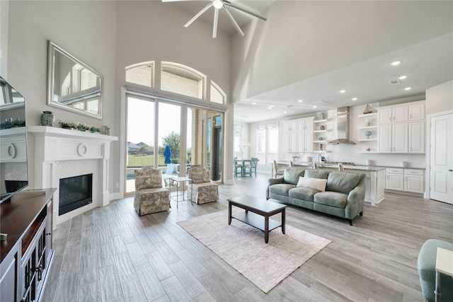 23935 Birchwood Lake Ln, Katy, TX 77493 - living area with light wood-style floors, a high ceiling, a ceiling fan, and a glass covered fireplace