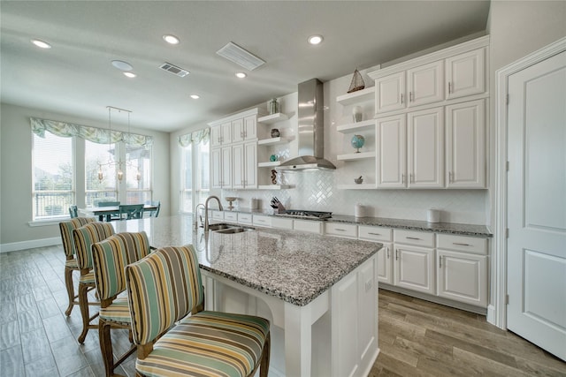 23935 Birchwood Lake Ln, Katy, TX 77493 - kitchen with open shelves, wall chimney range hood, white cabinets, a sink, and stainless steel gas stovetop