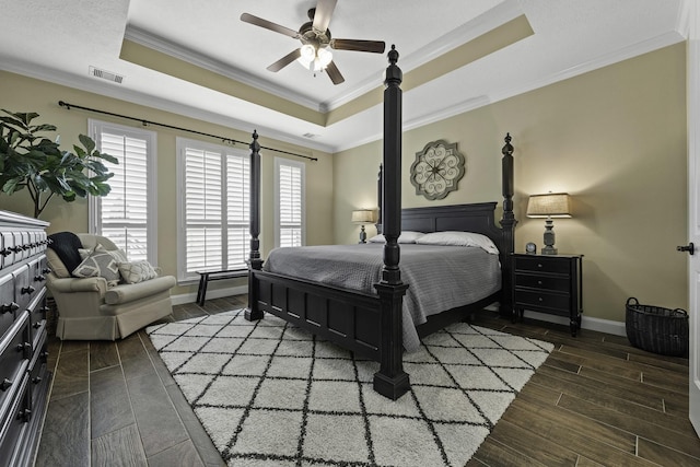 bedroom with a raised ceiling, ornamental molding, wood finished floors, and visible vents
