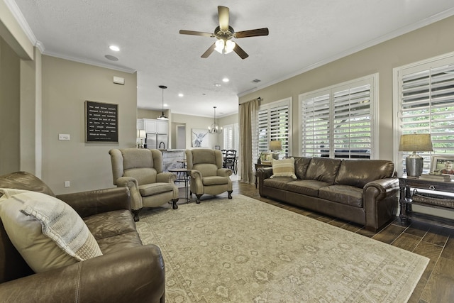 living area with a healthy amount of sunlight, crown molding, ceiling fan with notable chandelier, and dark wood-style flooring
