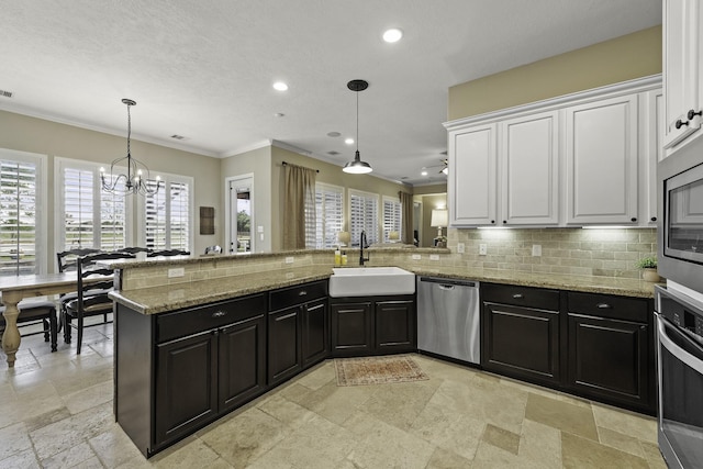 kitchen featuring appliances with stainless steel finishes, a sink, stone tile floors, white cabinetry, and tasteful backsplash