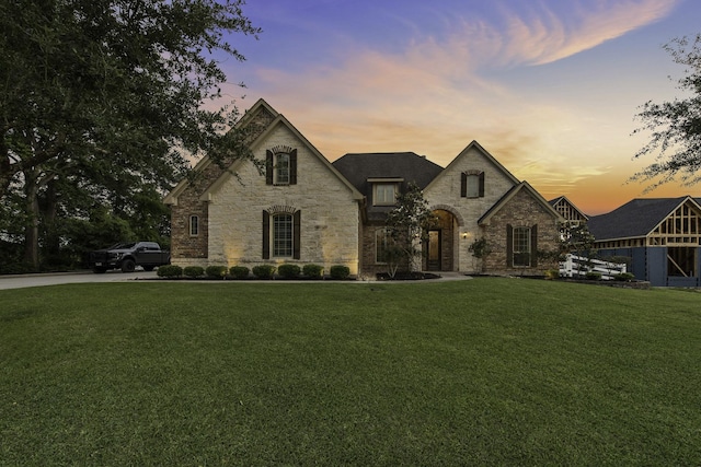 french country home featuring stone siding and a front lawn