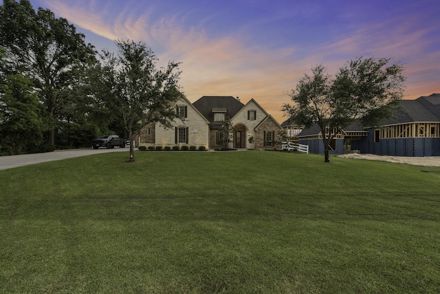 french country style house featuring a lawn and stone siding