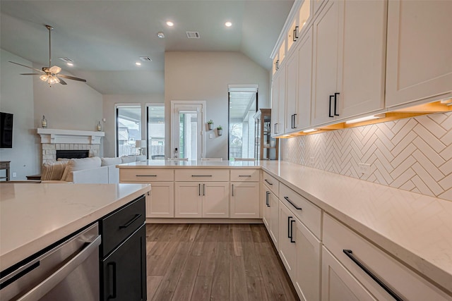 2502 Forest Side Ct, Missouri City, TX 77459 - kitchen featuring a ceiling fan, decorative backsplash, vaulted ceiling, light wood-style floors, and a fireplace