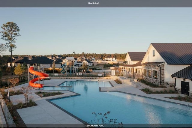 pool featuring a residential view, fence, a water slide, and a patio