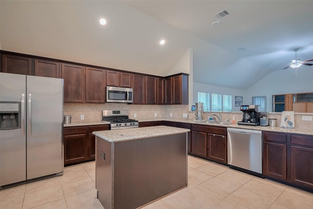 2903 Blue Mist Bnd, Brookshire, TX 77423 - kitchen featuring stainless steel appliances, light tile patterned floors, backsplash, dark brown cabinets, and lofted ceiling