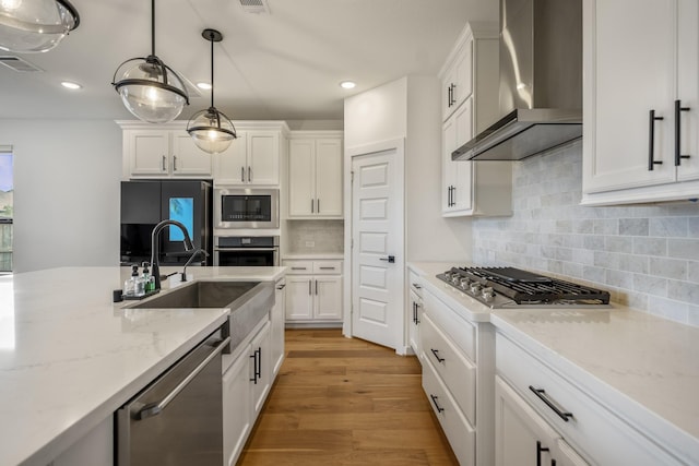 kitchen featuring a sink, white cabinets, stainless steel appliances, and wall chimney exhaust hood