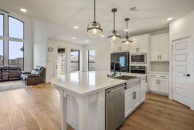 kitchen featuring stainless steel appliances, visible vents, white cabinetry, and light wood-type flooring