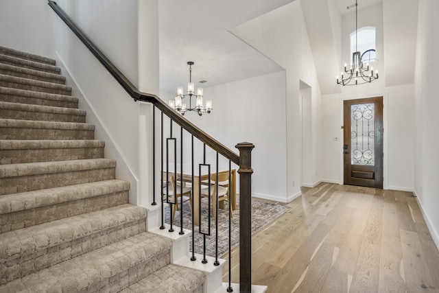 foyer entrance featuring a high ceiling, a notable chandelier, stairway, and light wood-type flooring