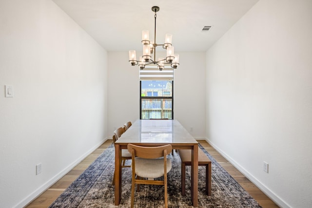 dining area with baseboards, visible vents, light wood-type flooring, and a chandelier