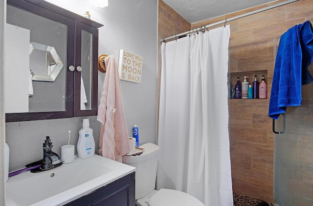 bathroom with vanity, a textured ceiling, toilet, and a shower stall