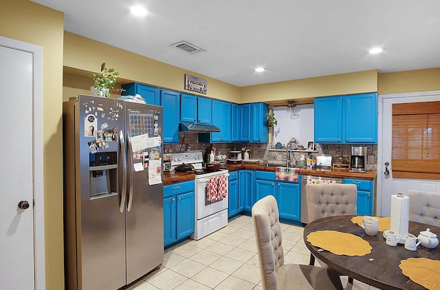 kitchen with blue cabinetry, stainless steel appliances, backsplash, under cabinet range hood, and visible vents