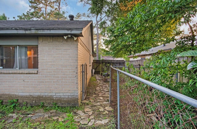 view of side of home featuring brick siding and fence