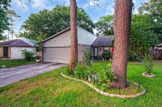 view of front of house featuring an attached garage, driveway, brick siding, and a front yard