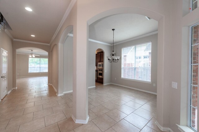 foyer featuring arched walkways, baseboards, ornamental molding, and ceiling fan with notable chandelier