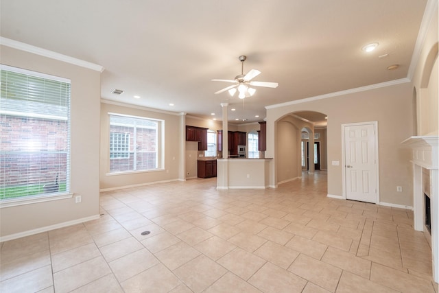 unfurnished living room with crown molding, arched walkways, plenty of natural light, and ceiling fan
