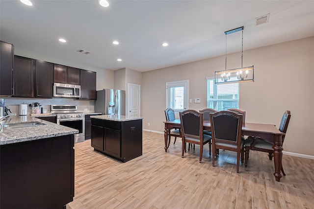 kitchen with appliances with stainless steel finishes, light wood-type flooring, visible vents, and a center island