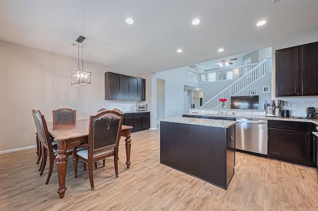 kitchen with a kitchen island, light stone counters, light wood-style flooring, ceiling fan with notable chandelier, and dishwasher