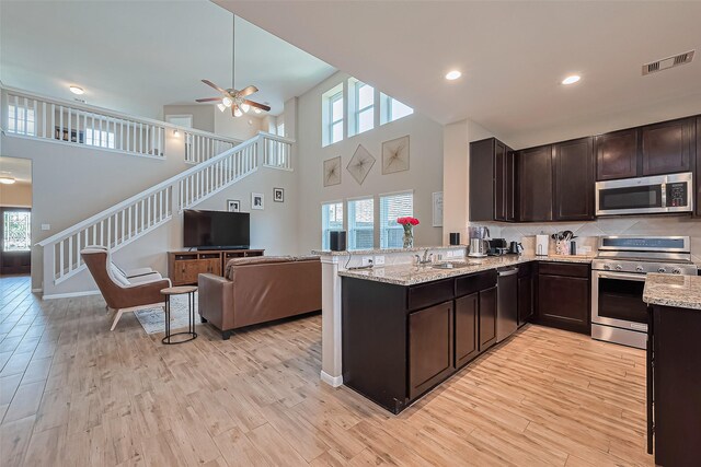 kitchen with plenty of natural light, open floor plan, dark brown cabinets, and stainless steel appliances
