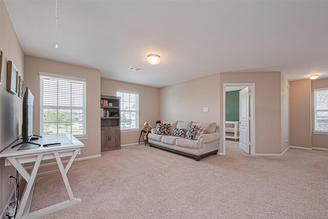 living room featuring radiator, baseboards, light carpet, and visible vents