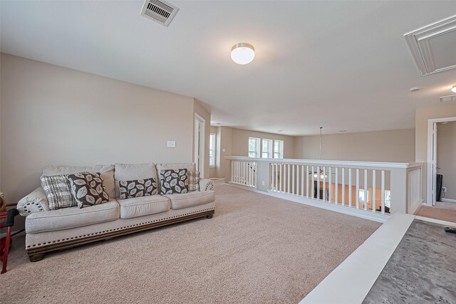 carpeted living room featuring visible vents, attic access, and baseboards