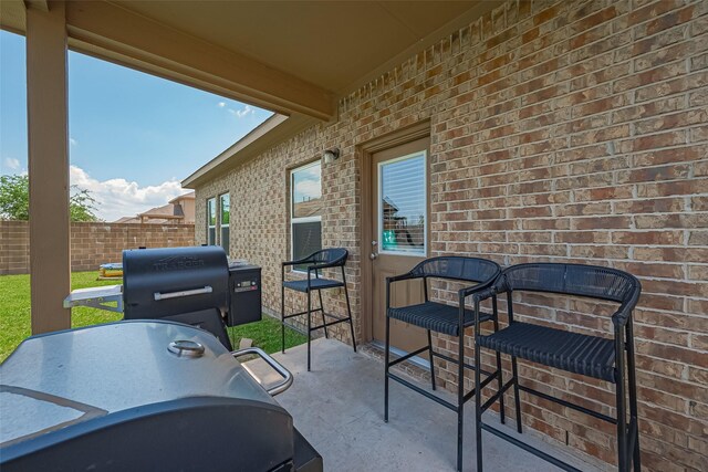 view of patio with fence and a grill