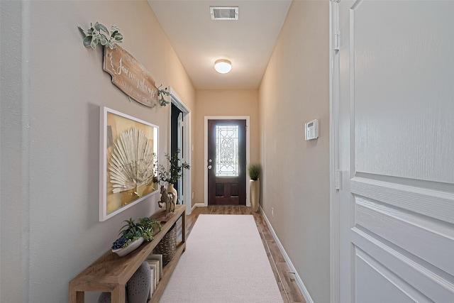 doorway to outside featuring visible vents, baseboards, and wood finished floors
