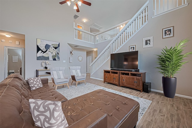 11351 Needlerock Ct, Humble, TX 77396 - living area with ceiling fan, a towering ceiling, baseboards, light wood-style floors, and stairs