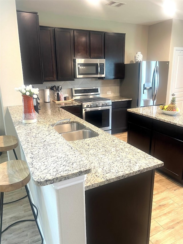 11351 Needlerock Ct, Humble, TX 77396 - kitchen featuring appliances with stainless steel finishes, light stone counters, a peninsula, and tasteful backsplash