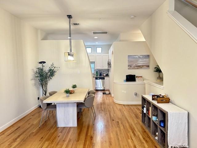dining room featuring baseboards, visible vents, and light wood-style floors