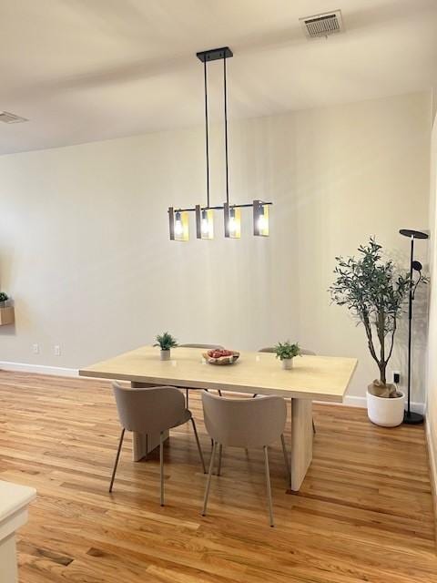 dining room with baseboards, light wood-type flooring, and visible vents