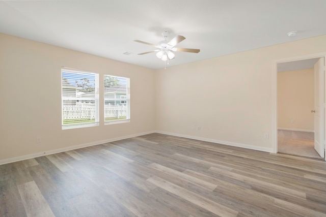 empty room featuring baseboards, light wood finished floors, and ceiling fan