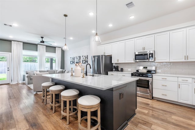 kitchen with stainless steel appliances, visible vents, and light wood finished floors