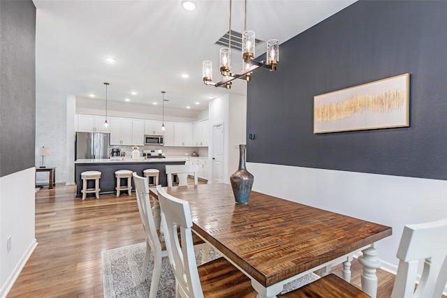 dining area with baseboards, recessed lighting, light wood-style flooring, and a chandelier