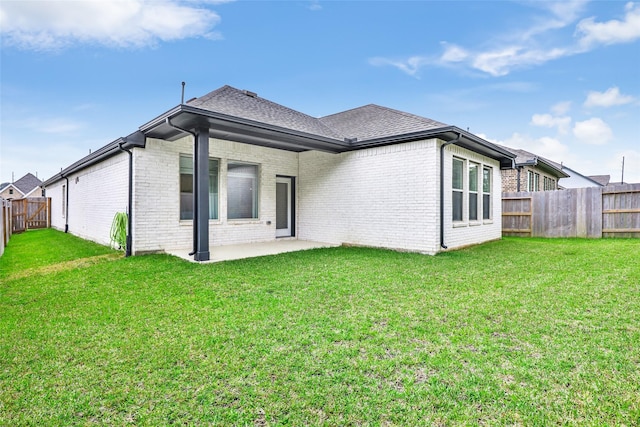 back of property featuring roof with shingles, brick siding, a fenced backyard, a patio, and a yard