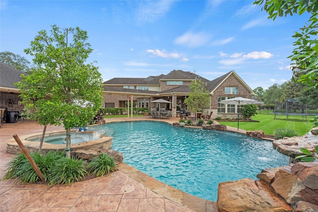outdoor pool with a patio, a trampoline, an in ground hot tub, and a lawn