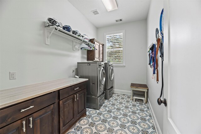 clothes washing area featuring visible vents, cabinet space, baseboards, and washing machine and clothes dryer