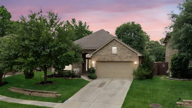 view of front of home with a shingled roof, an attached garage, brick siding, a front yard, and driveway