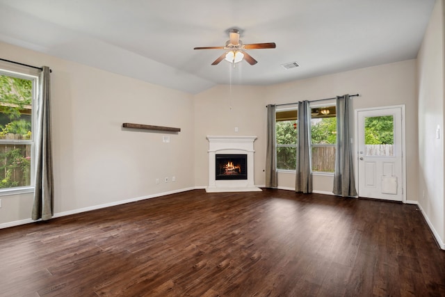 unfurnished living room featuring visible vents, a ceiling fan, plenty of natural light, and a warm lit fireplace