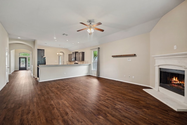 unfurnished living room featuring dark wood-style flooring, a warm lit fireplace, ceiling fan, arched walkways, and visible vents