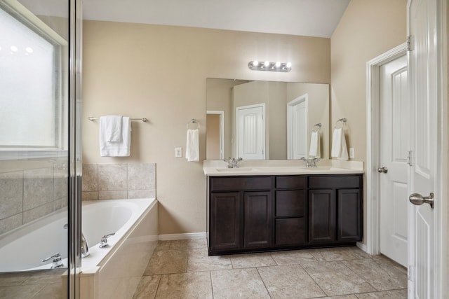 bathroom with baseboards, double vanity, a sink, and a bath