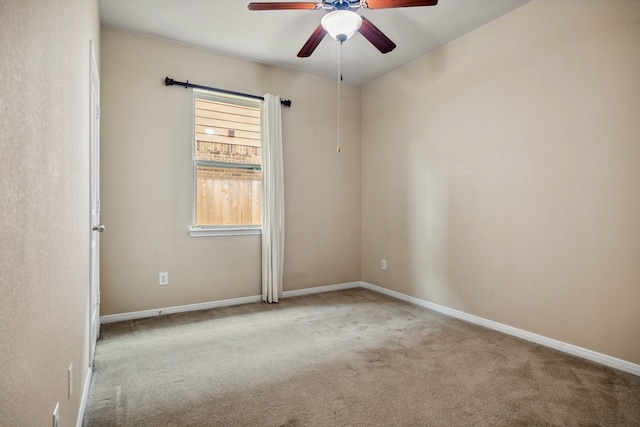 carpeted empty room with a ceiling fan and baseboards