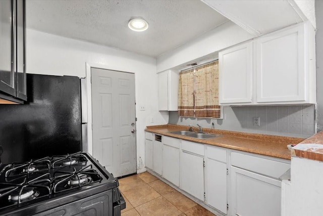 6201 Batterson St, Houston, TX 77026 - kitchen featuring white cabinets, light tile patterned flooring, black gas range oven, a sink, and freestanding refrigerator
