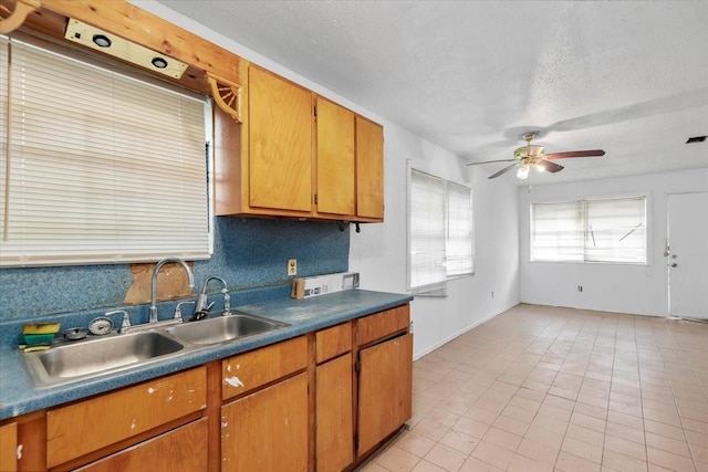6201 Batterson St, Houston, TX 77026 - kitchen featuring brown cabinetry, a sink, a textured ceiling, and a ceiling fan