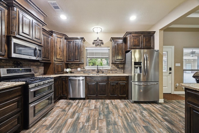 kitchen featuring dark brown cabinets, a sink, stainless steel appliances, dark wood-type flooring, and visible vents