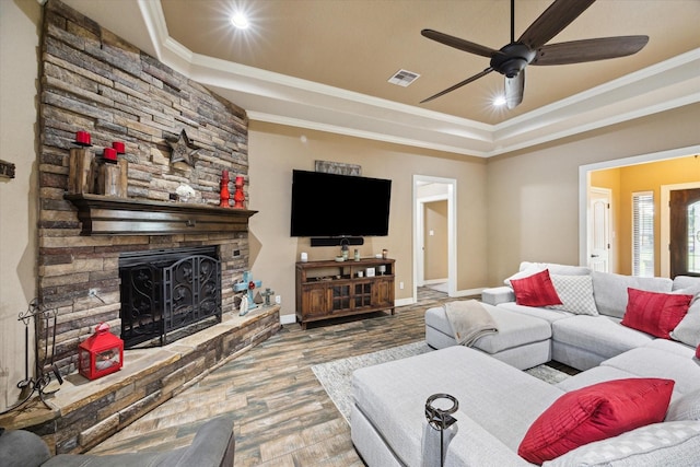 living area with ceiling fan, visible vents, wood finished floors, baseboards, and ornamental molding