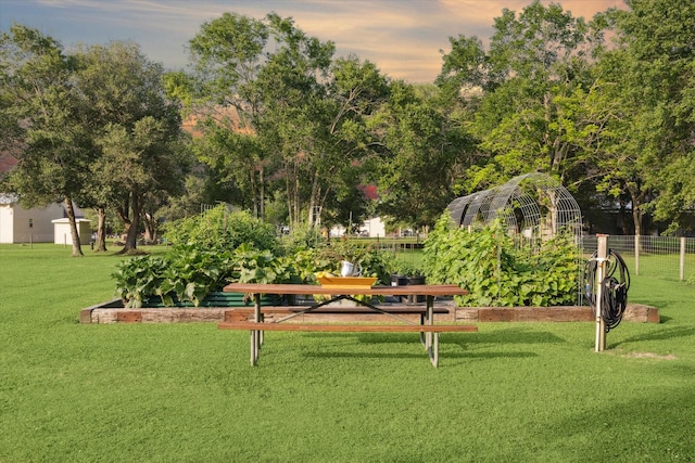 view of home's community with a yard, fence, and a vegetable garden