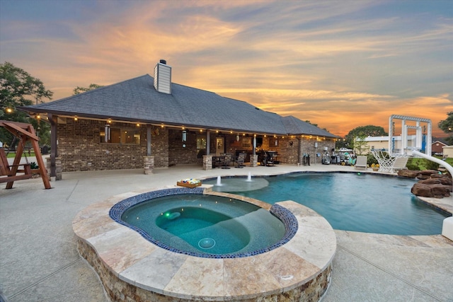 pool at dusk featuring a pool with connected hot tub and a patio area