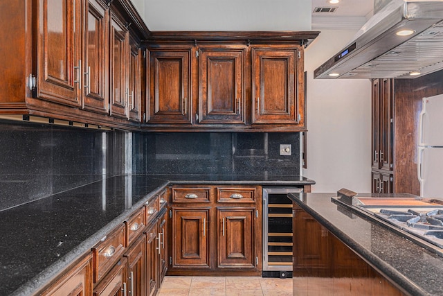 kitchen with freestanding refrigerator, dark stone counters, decorative backsplash, range hood, and wine cooler